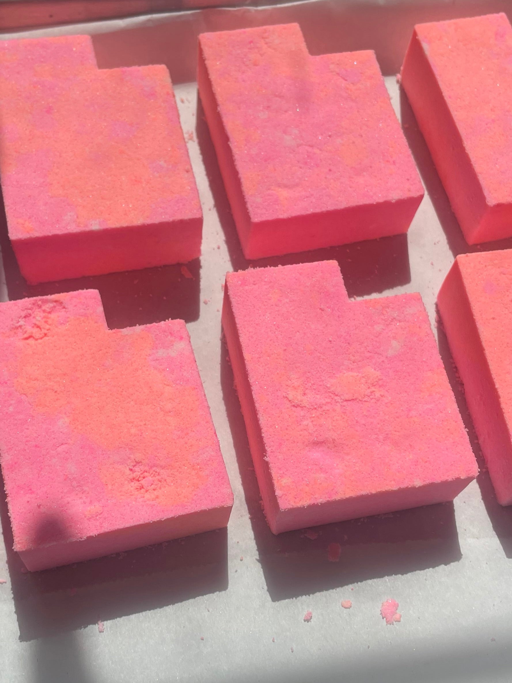 Pink bath bombs in a tray on a wooden surface